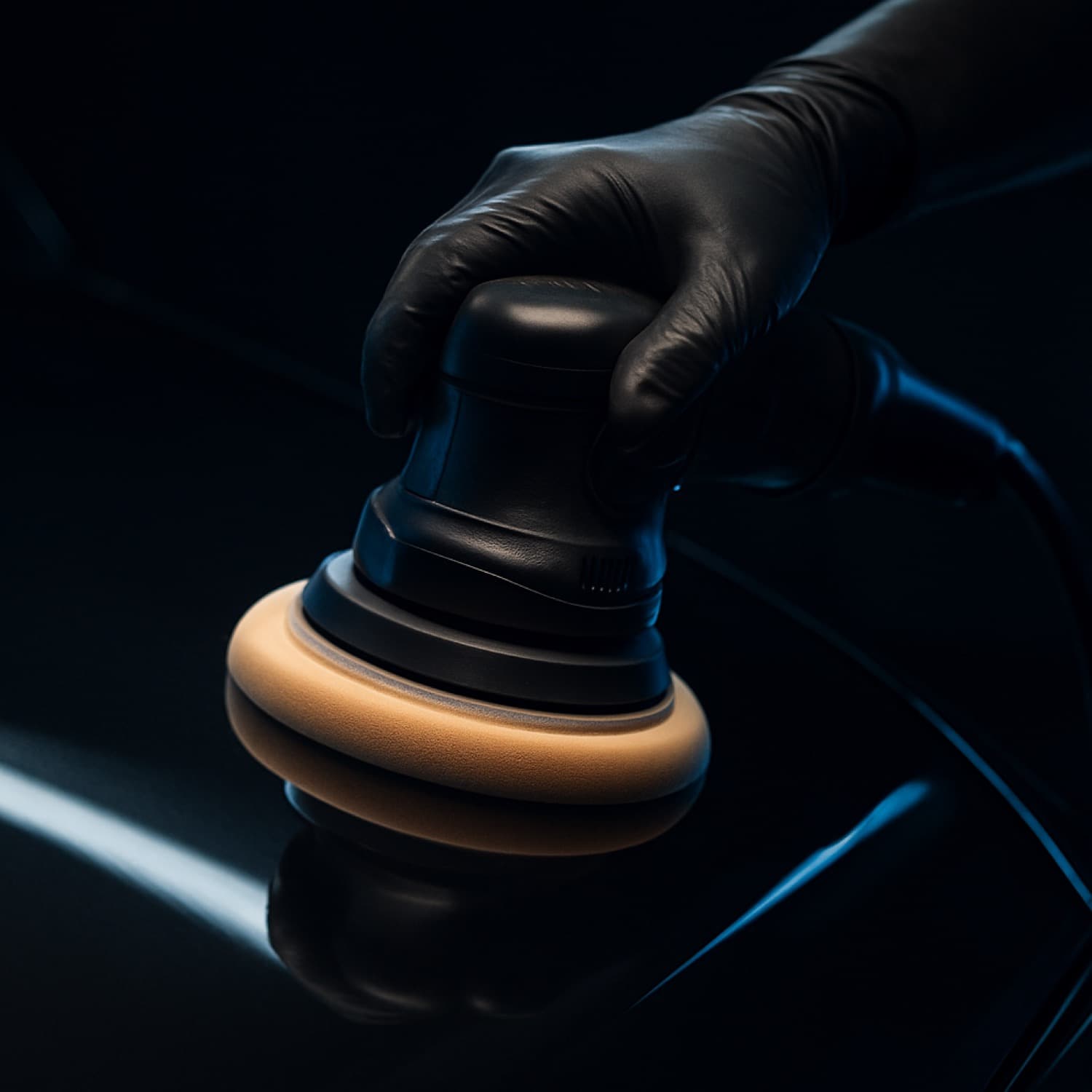 Machine polishing a dark car panel during a full detail